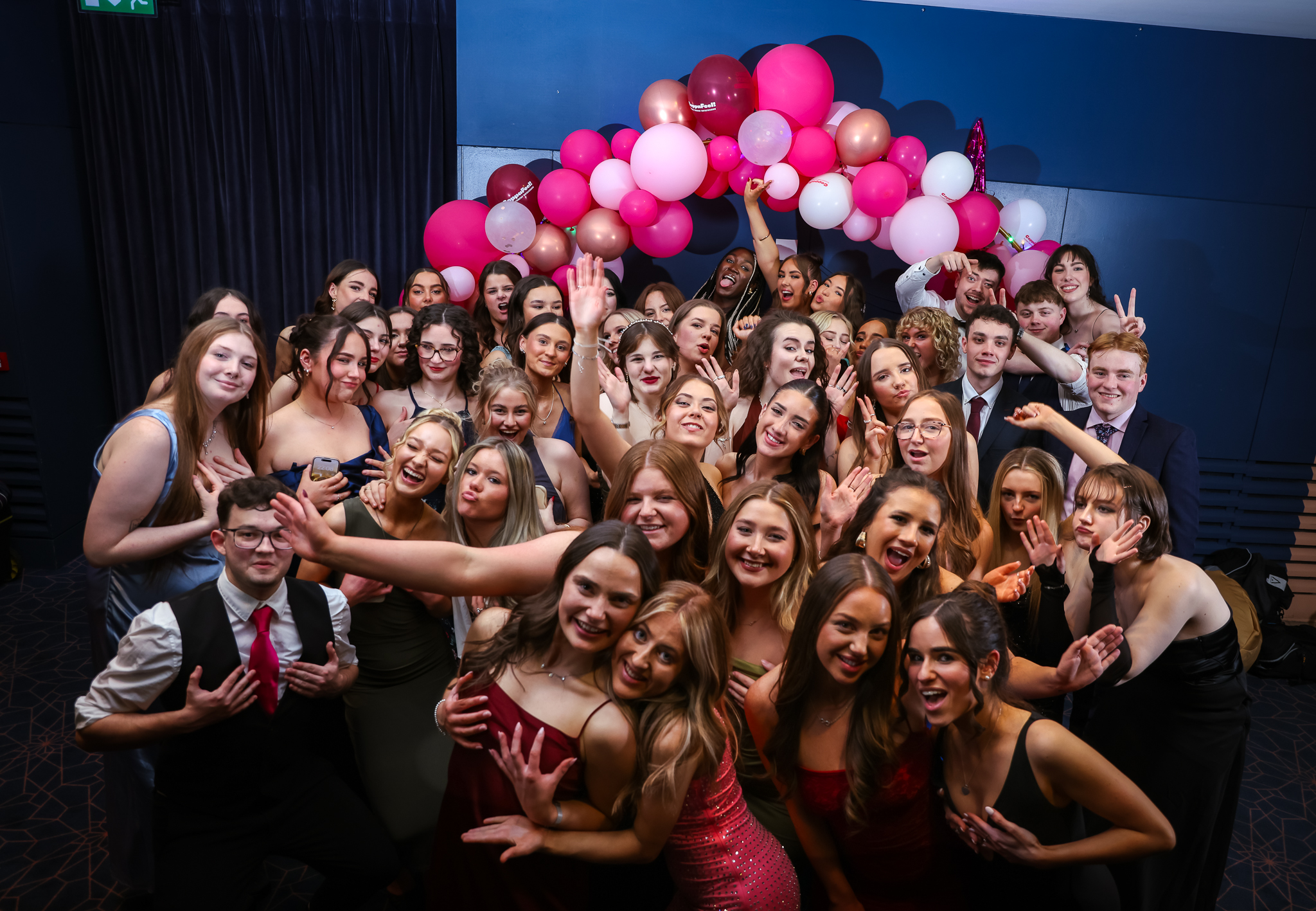 A large group of young people in front of a balloon arch