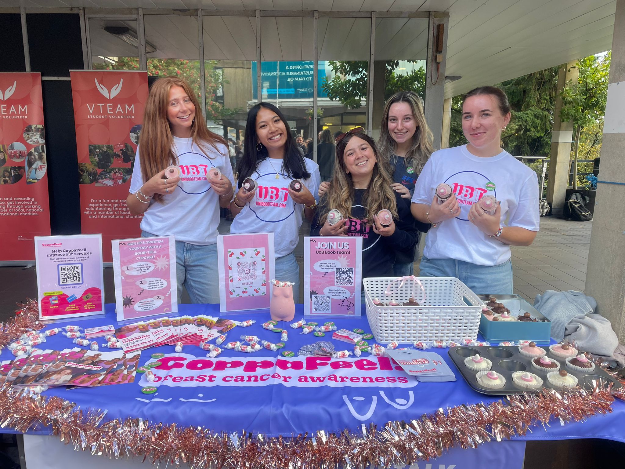 A group of young people stood at an awareness stand for CoppaFeel!